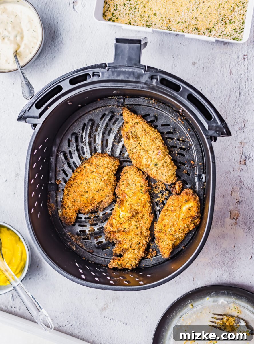 Crispy Golden Air Fryer Catfish 7 Four perfectly cooked, golden-brown catfish fillets in the air fryer basket after cooking.
