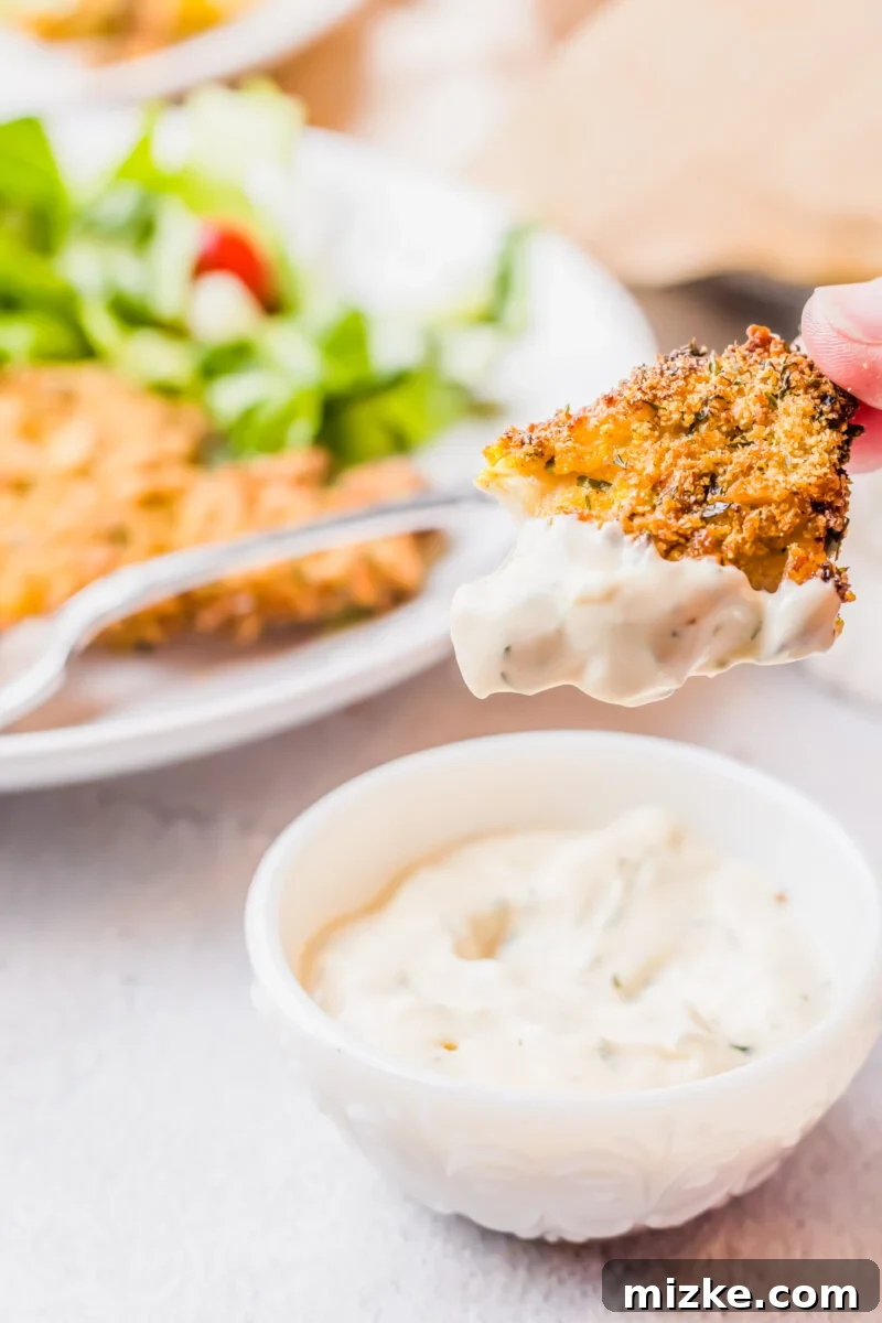 Crispy Golden Air Fryer Catfish 9 A piece of crispy air fryer catfish being dipped into a dollop of creamy tartar sauce.