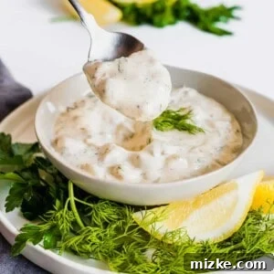 A close-up shot of the finished homemade tartar sauce, rich and creamy, ready to be served in a small white bowl.