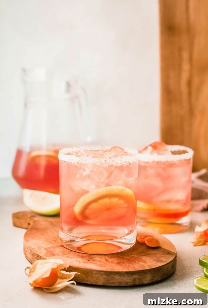 Sun-Kissed Rosé Sangria 5 A slice of lemon is floating in a cup filled with ice and pink sangria.