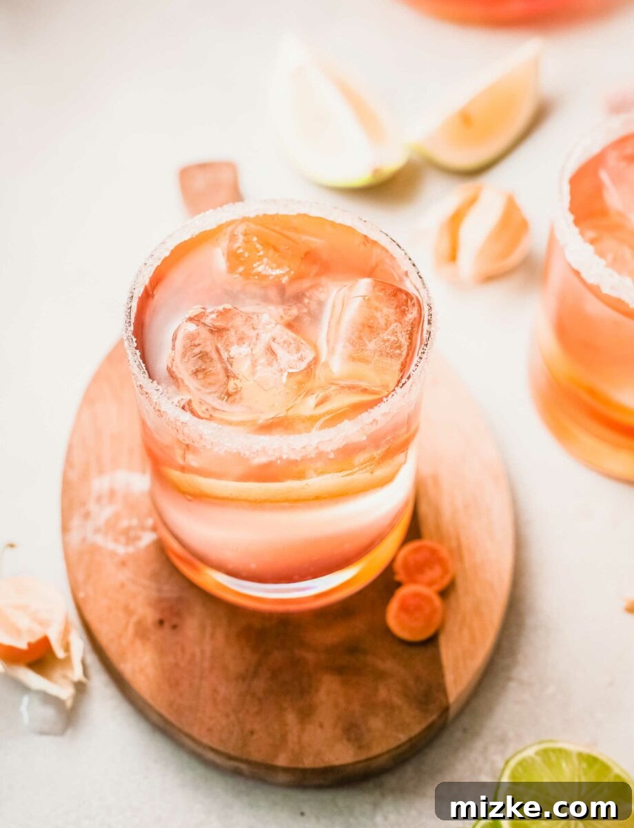 Sun-Kissed Rosé Sangria 6 A glass of citrus rosé sangria, garnished with an orange slice, is placed on a rustic wooden surface.