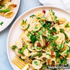A close-up of a bowl of Asparagus, Peas, and Pancetta Pasta, garnished with fresh herbs.