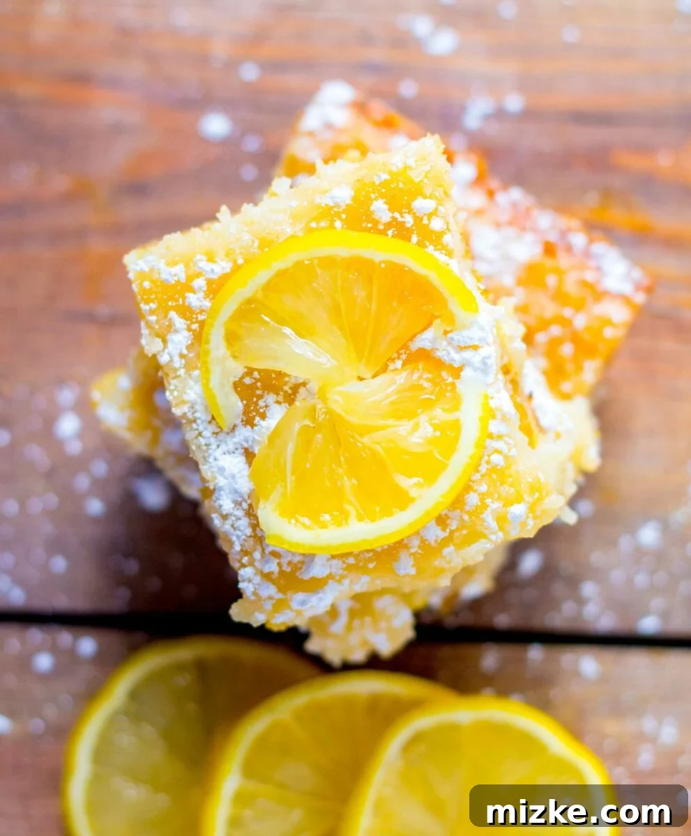 Luscious Lemon Gooey Butter Cake 6 Lemon slices and cake pieces are placed on top of a wooden surface.