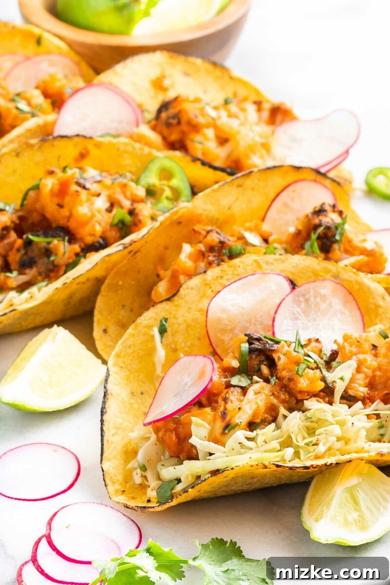 Freshly cut lime slices are elegantly arranged next to a serving of cauliflower tinga tacos, highlighting the citrus's role as a vital flavor enhancer.