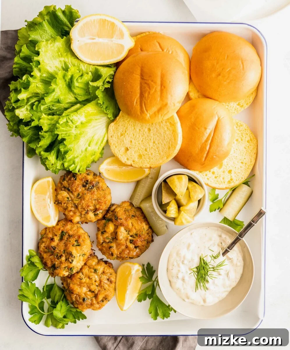 Ultimate Crab Cake Sandwiches 3 A vibrant culinary spread featuring golden crab cakes, lightly toasted brioche buns, crisp green lettuce, and a creamy, tangy sauce, all arranged on a pristine white serving platter, inviting an immediate feast.