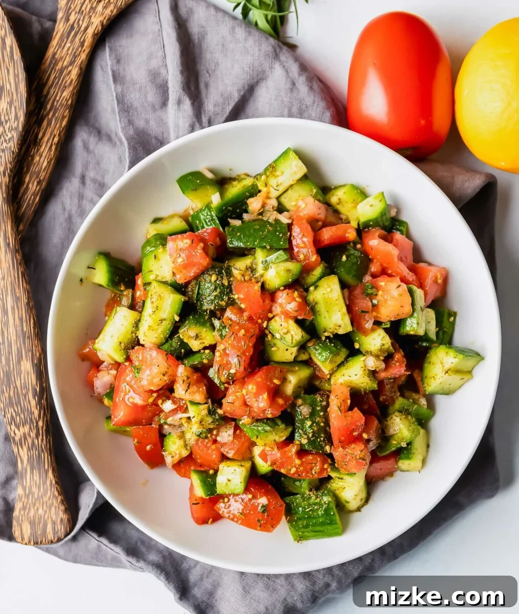 Mediterranean Za'atar Cucumber Tomato Salad 4 A simple yet elegant white bowl holds the vibrant Za'atar cucumber tomato salad, placed on a textured gray tea cloth, highlighting its fresh appeal.
