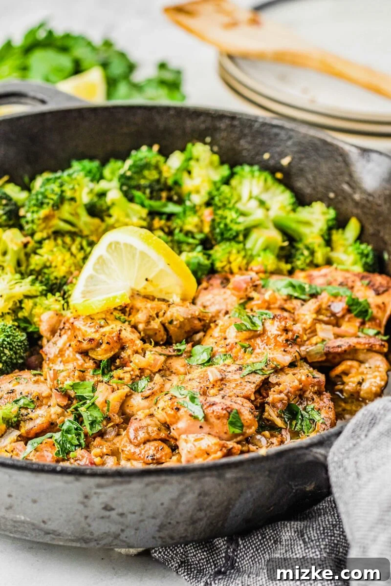 Lemon garlic chicken thighs in a skillet are generously garnished with fresh parsley and rosemary sprigs.