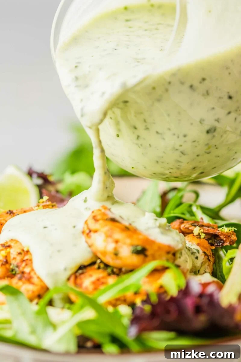 Zesty Cilantro Lime Cream Kick 4 Creamy cilantro lime dressing being drizzled generously onto a fresh shrimp salad.