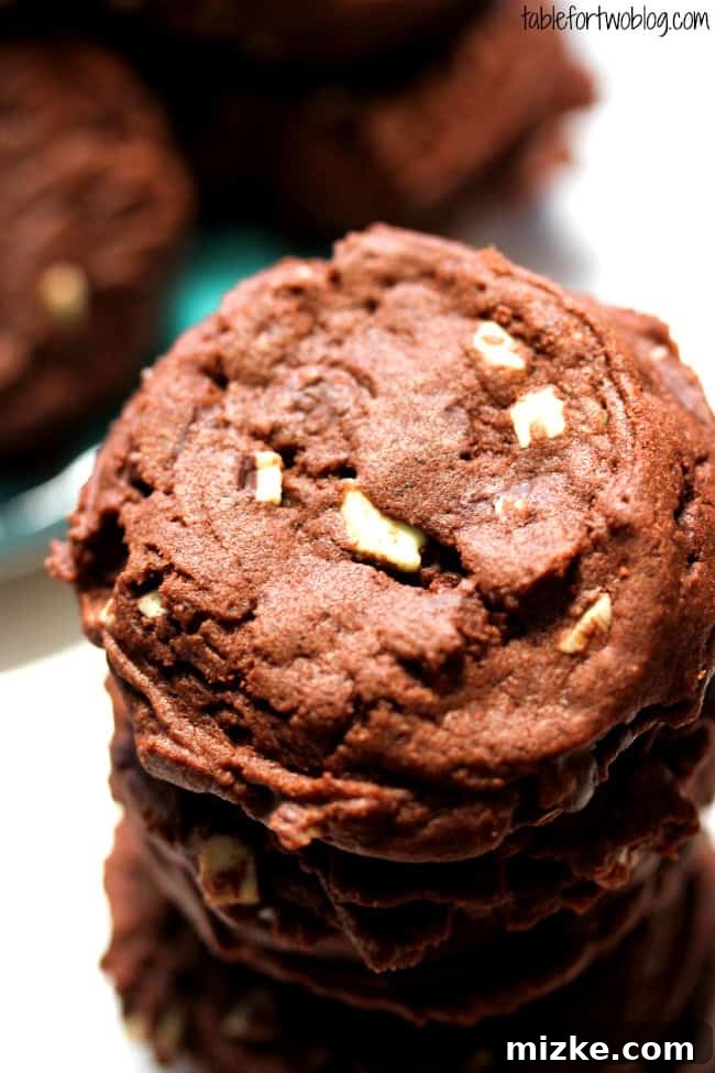 A plate stacked high with warm Mint Chocolate Pudding Cookies, showcasing their appealing chocolate color and mint flecks.