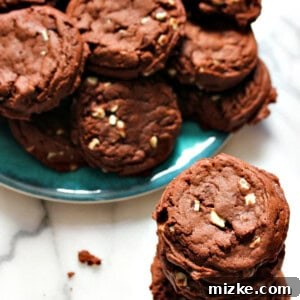 A close-up of a single Mint Chocolate Pudding Cookie, showcasing its rich chocolate base and melted green Andes mint pieces.