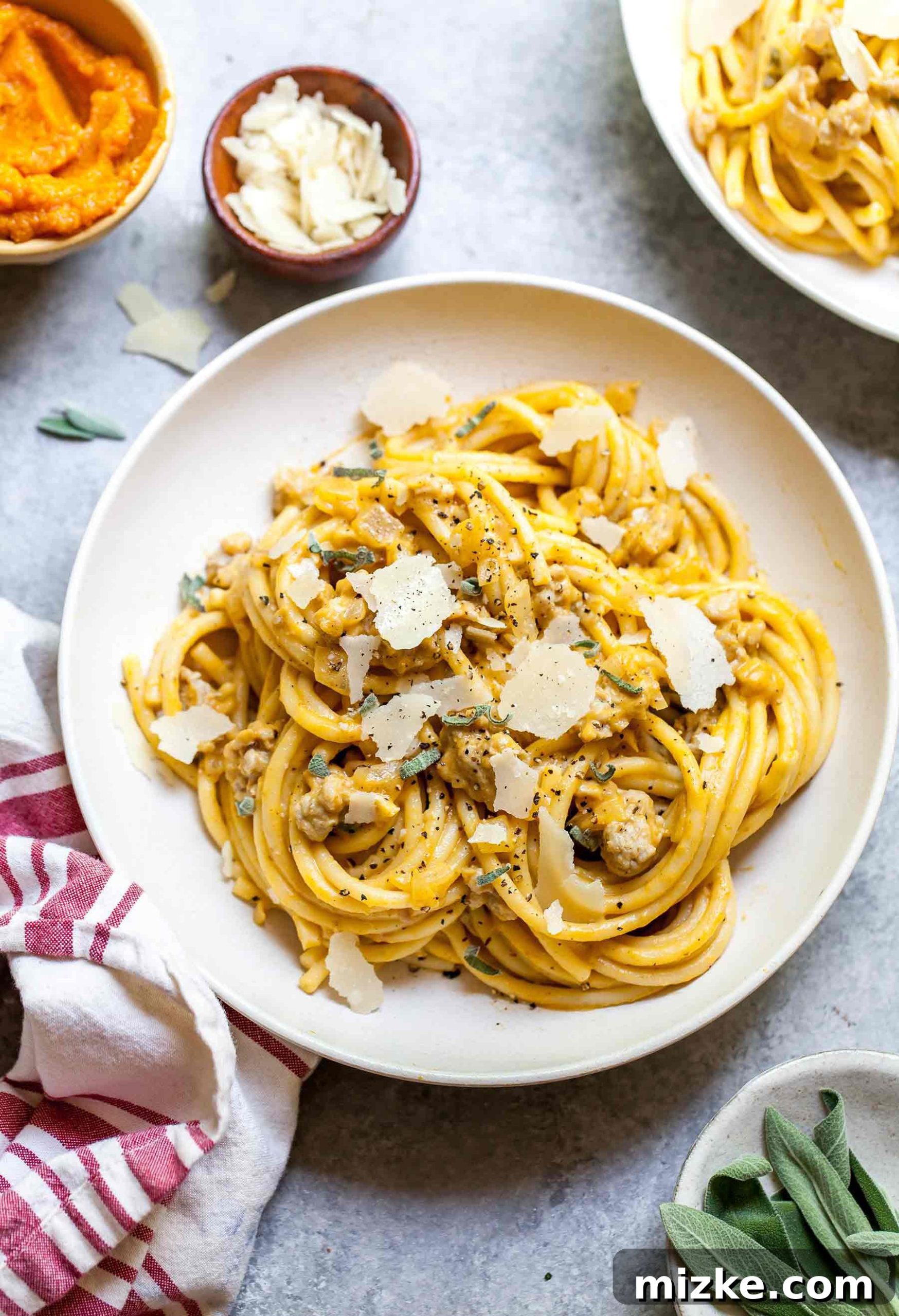 Autumn Spiced Pumpkin Pasta with Turkey Sausage 2 Overhead shot of creamy pumpkin pasta with chicken sausage in white bowl, garnished with fresh herbs
