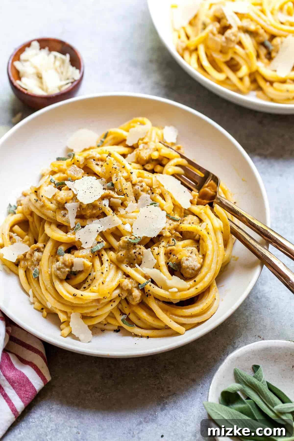 Autumn Spiced Pumpkin Pasta with Turkey Sausage 3 Overhead shot of creamy pumpkin pasta with turkey sausage in white bowls with gold forks, ready to serve