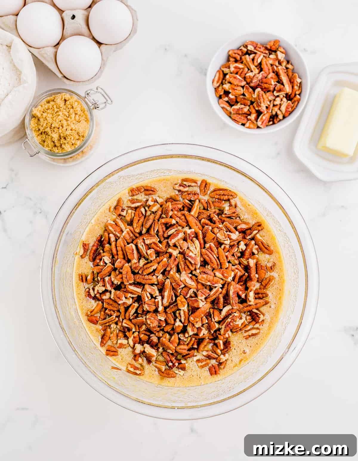 Golden Pecan Pie Squares 10 Roughly chopped pecans are generously sprinkled over the smoothly whisked filling mixture in a clear bowl, ready to be gently folded in.