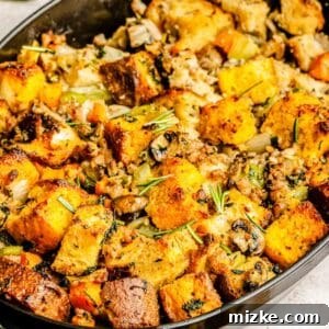 cornbread stuffing in a large black cast iron baking dish with fresh rosemary sprinkled on top