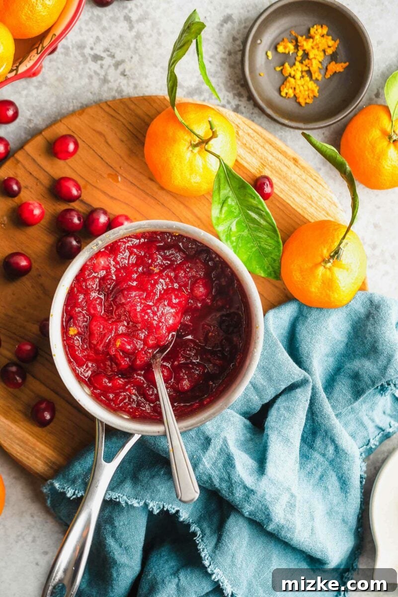 This simple 4-ingredient cranberry orange sauce takes minutes to make and tastes infinitely better than canned versions. A holiday essential! overhead shot of cranberry orange sauce simmering in a saucepan