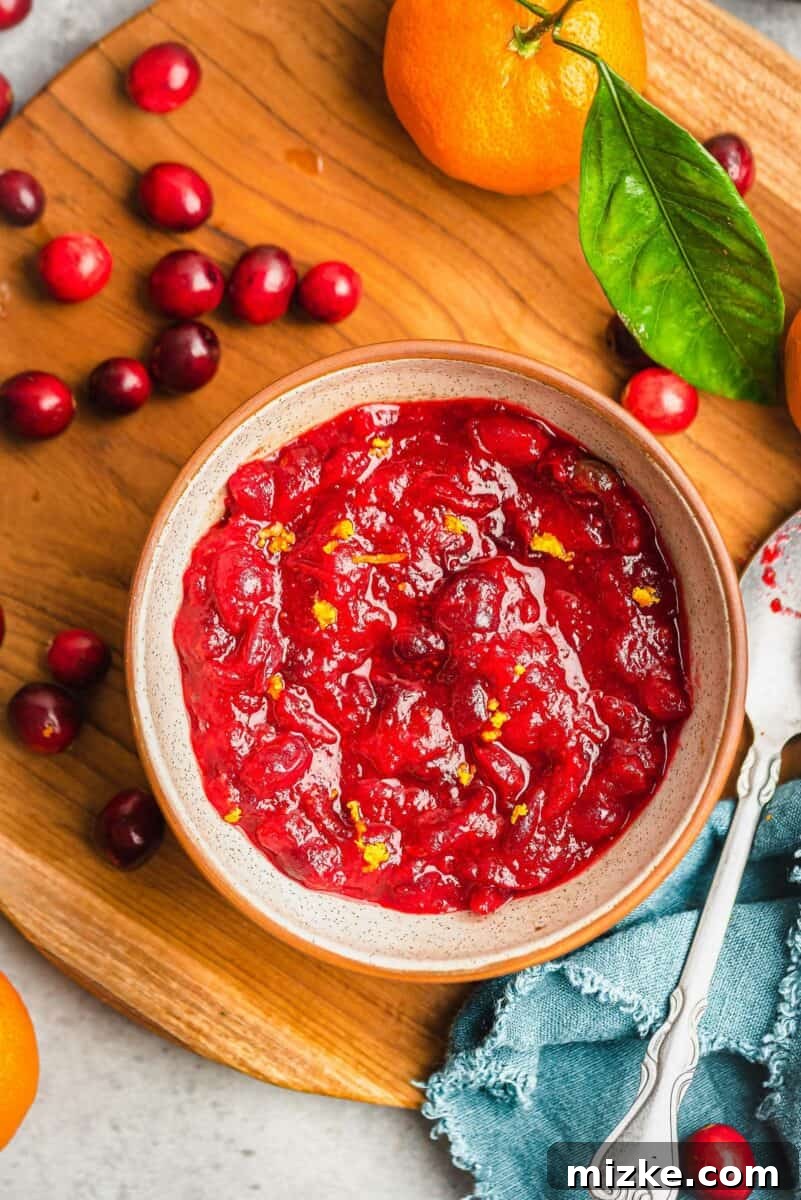 A vibrant and delicious homemade cranberry orange sauce, ready to be served. cranberry orange sauce in a brown ceramic bowl, overhead shot