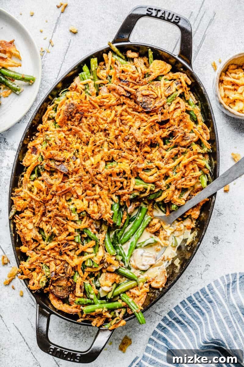 Classic Homemade Green Bean Casserole on a Thanksgiving table, beautifully golden and bubbly, with fresh green beans and crispy fried onions visible.