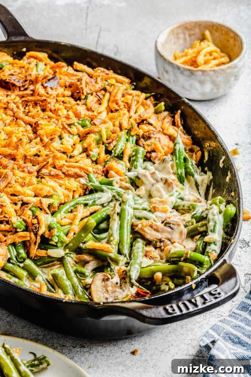 Freshly baked homemade green bean casserole, golden and bubbling, showcasing its tender beans and crunchy fried onion topping, ready to be served at Thanksgiving.