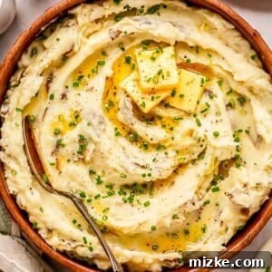 Heavenly Garlic Mashed Potatoes 5 A beautifully presented bowl of garlic mashed potatoes, adorned with fresh chives and melting butter, ready to be served.
