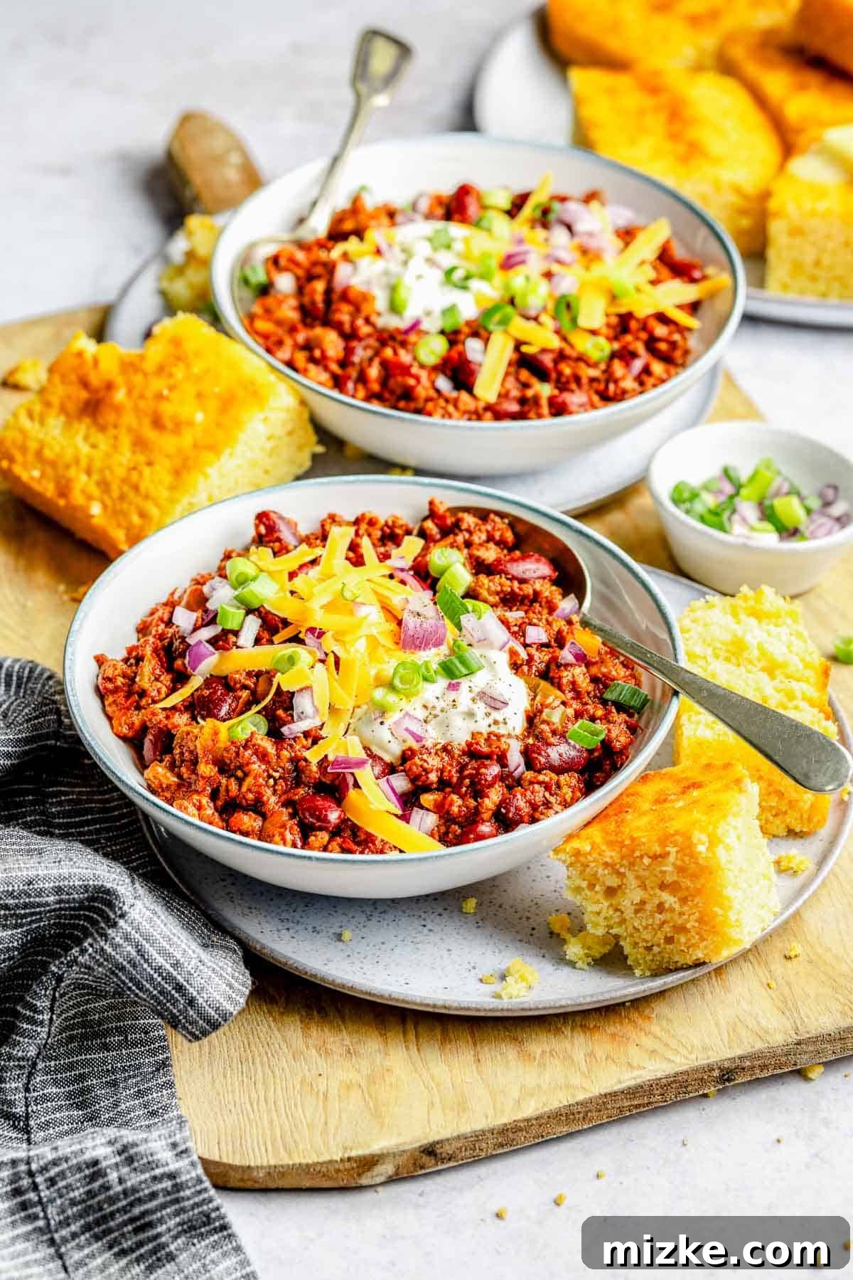 Delicious bowls of slow cooker chili, richly topped and ready for a satisfying meal. Two generous bowls of slow cooker chili, beautifully garnished with a variety of toppings like cheese, sour cream, and fresh herbs, ready to be served.