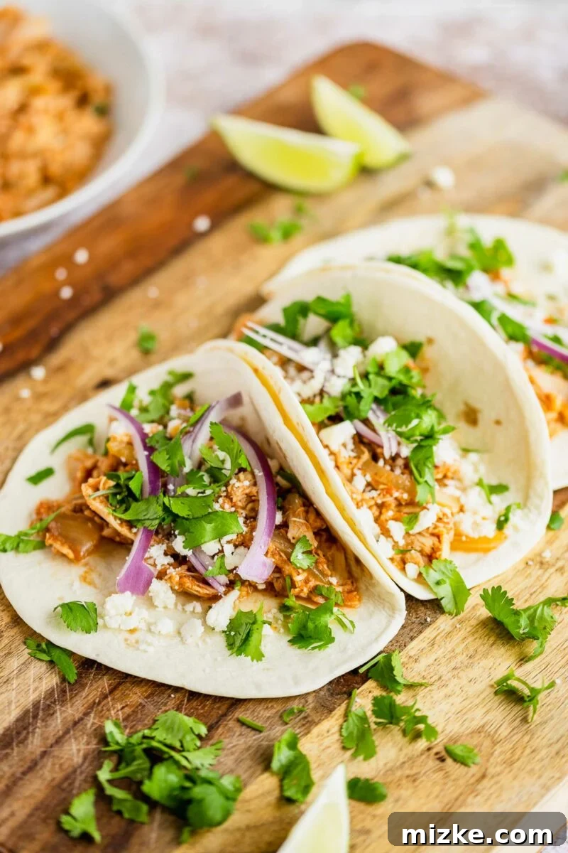 Easy Slow Cooker Chicken Tinga Tacos 4 A fully assembled chicken tinga taco showcasing the shredded chicken, cheese, onions, and cilantro.