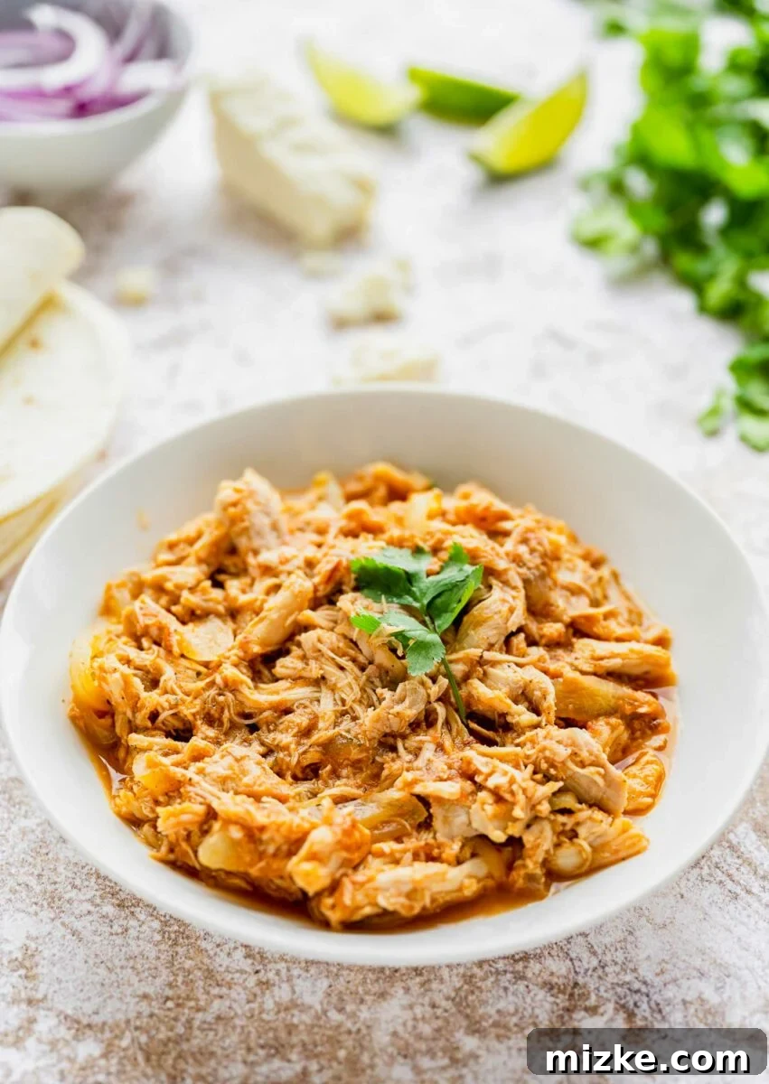 Easy Slow Cooker Chicken Tinga Tacos 5 A white bowl brimming with the rich, shredded chicken tinga meat, ready for serving.