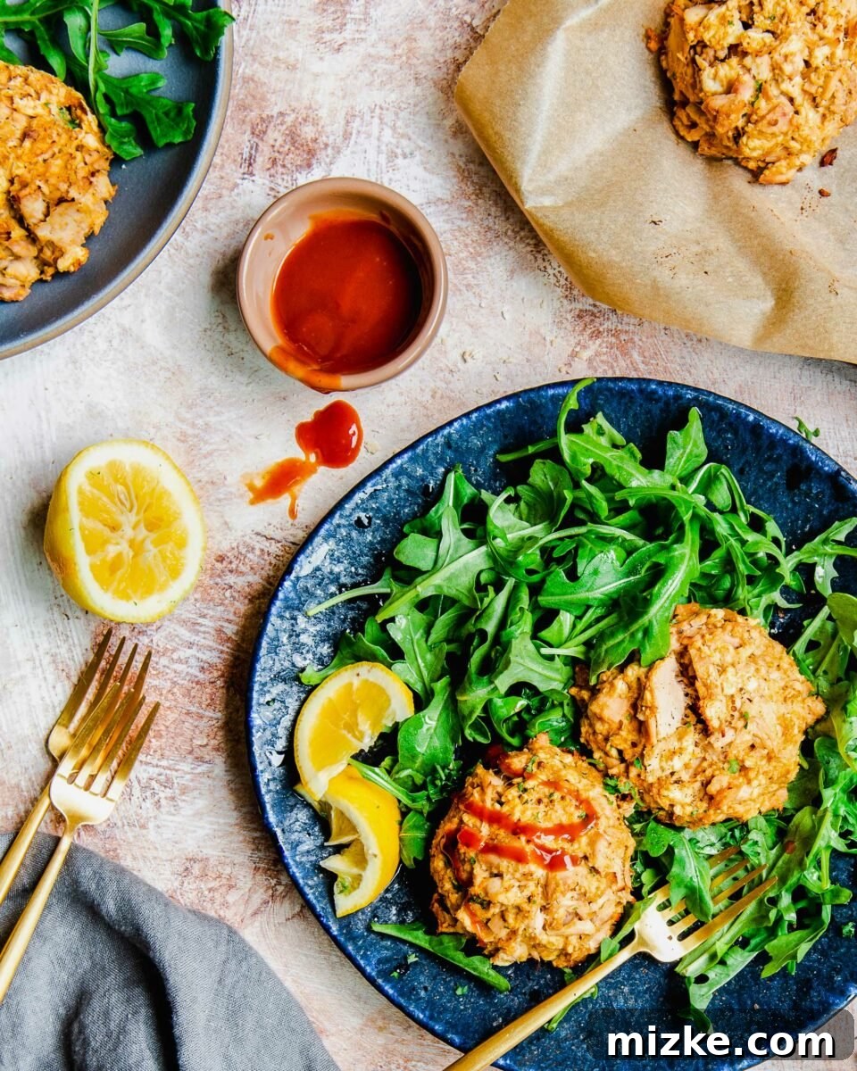 Golden Tuna Patties 3 Rich cocktail sauce is elegantly drizzled over a perfectly baked tuna cake, highlighting its golden crust.