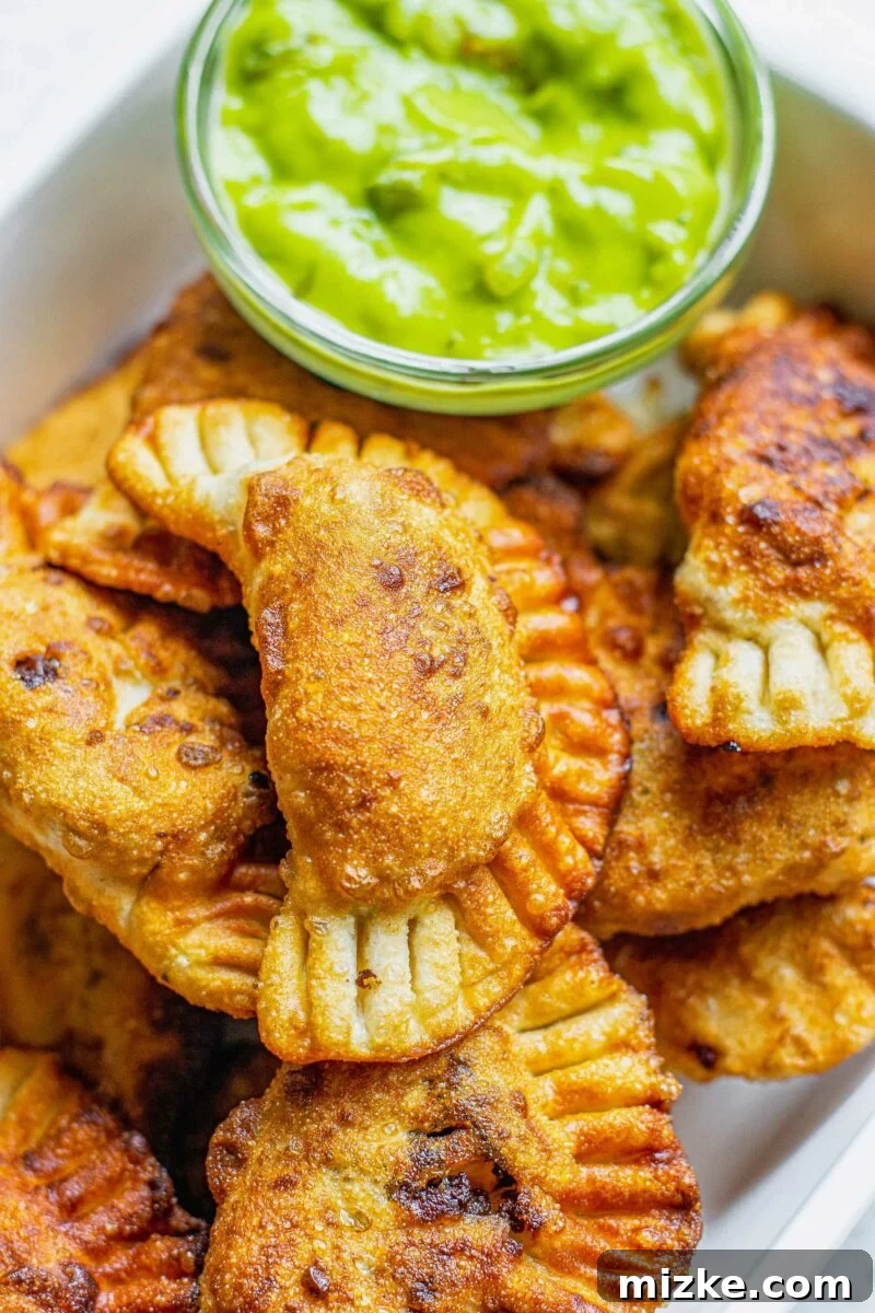 A close-up view of golden-brown, perfectly cooked empanadas resting on a clean white plate, ready to be served.