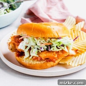 Potato chips are placed next to a chicken sandwich.
