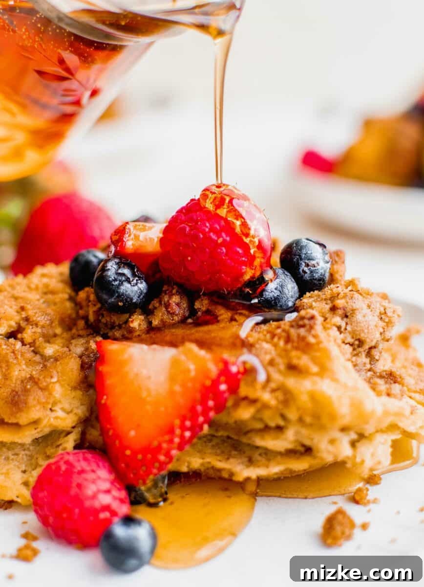 Irresistible Brown Sugar Streusel French Toast Bake 4 Syrup is being poured onto a serving of casserole.
