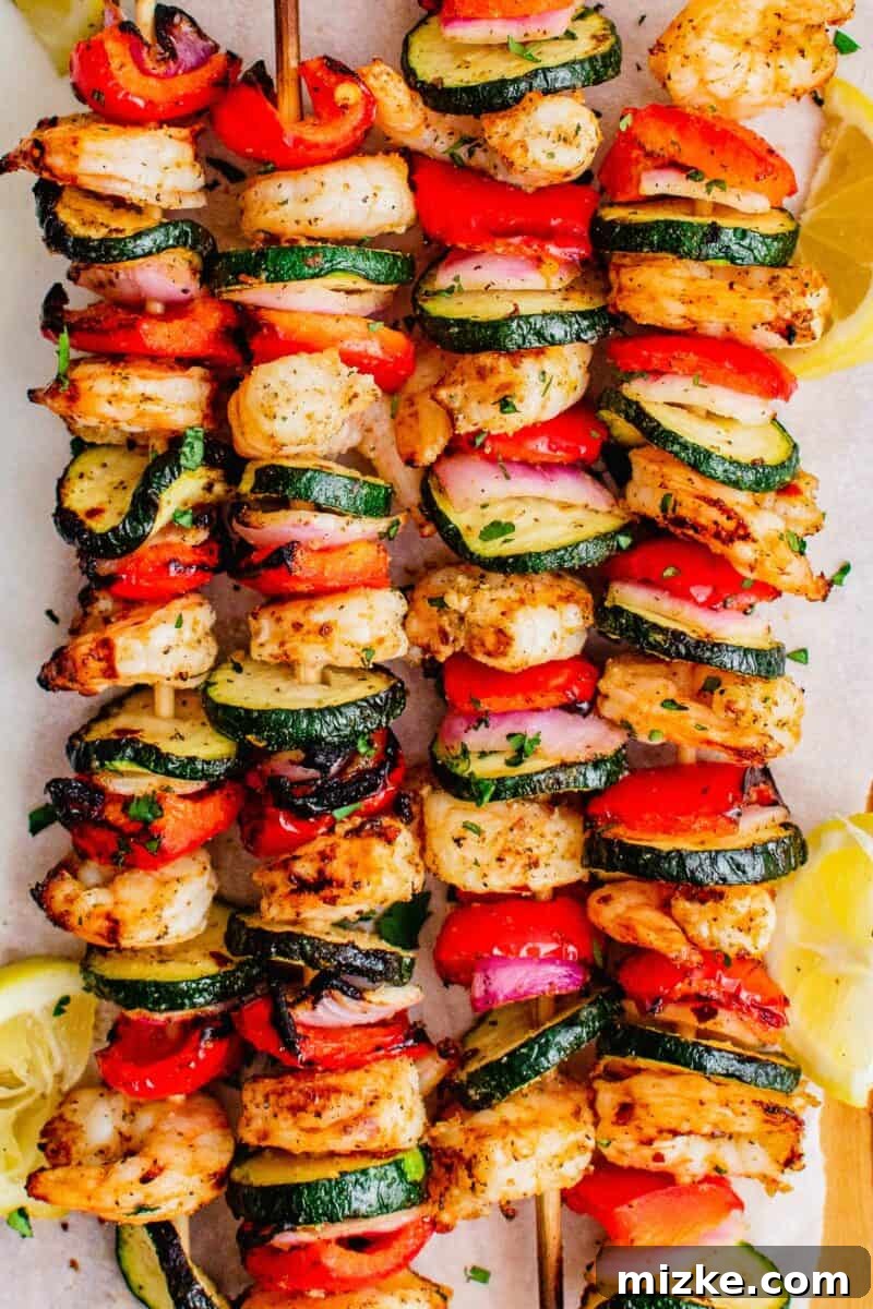 Smoky Grilled Shrimp Skewers 3 Four kebobs are placed next to each other on a white plate.