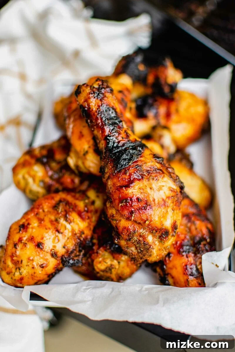 Smoky Dry Rub Grilled Drumsticks 3 Chicken legs are finished grilling, and parts of them are blackened.