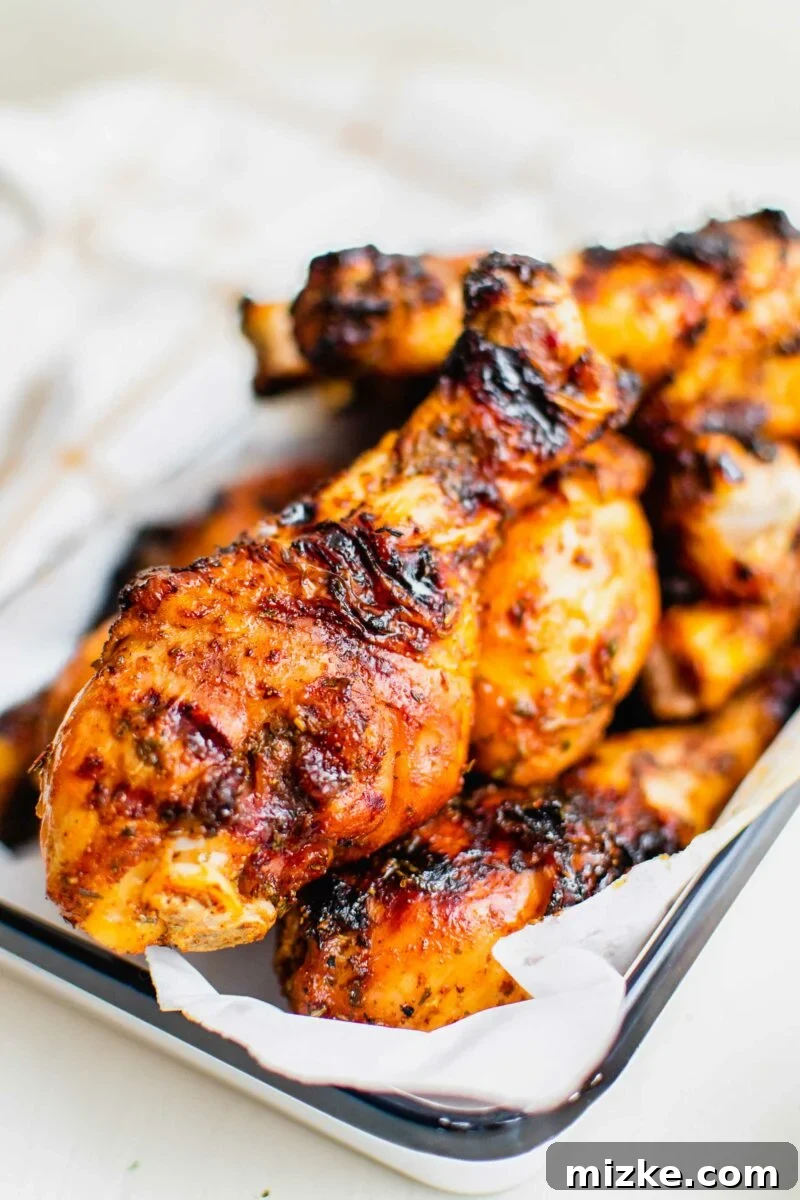 Smoky Dry Rub Grilled Drumsticks 4 Grilled chicken legs are placed on a sheet of parchment paper.