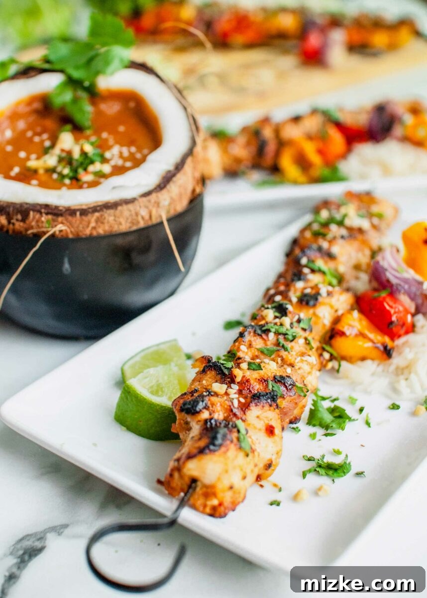 Tropical Coconut Chicken Satay 6 A hollowed-out coconut shell artfully presented, filled with a creamy, rich peanut dipping sauce, ready for serving.