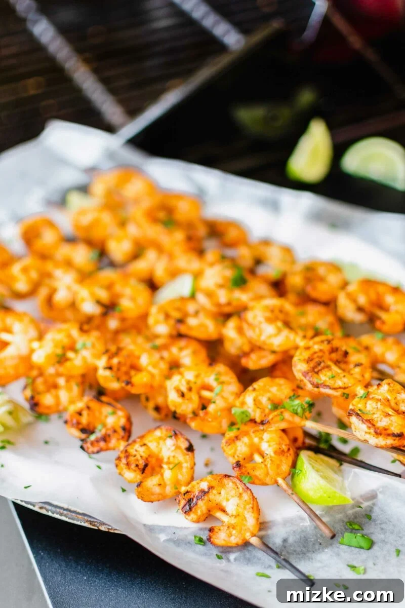 Flame-Kissed Baja Shrimp Skewers 2 Grilled shrimp skewers are on a sheet of parchment paper.