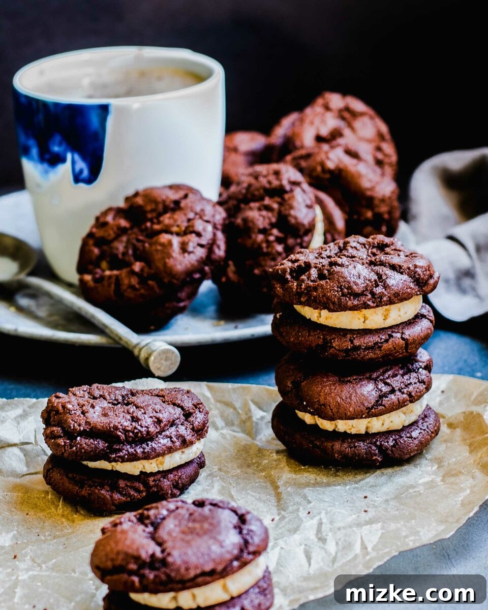 Frozen Mocha Latte Cookie Sandwiches 3 Freshly baked mocha latte ice cream sandwich cookies are neatly arranged on a sheet of parchment paper, cooling on a dark countertop, showcasing their rich color and inviting texture.