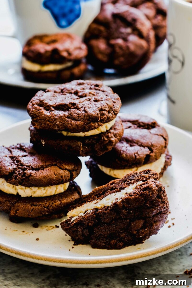 Frozen Mocha Latte Cookie Sandwiches 4 Three perfectly assembled mocha latte ice cream sandwich cookies are presented on a pristine white plate, showcasing their inviting layers of chocolate cookie and creamy mocha filling.