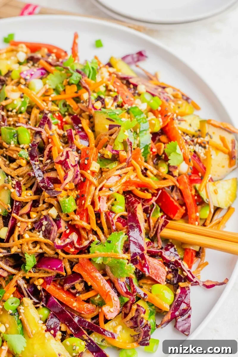 Velvety Peanut Soba Salad 5 Chopsticks are placed on a white plate topped with soba noodle salad.