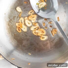 Refreshing Chicken & Veggie Rolls 4 browned garlic slices in a metal skillet with a metal spoon