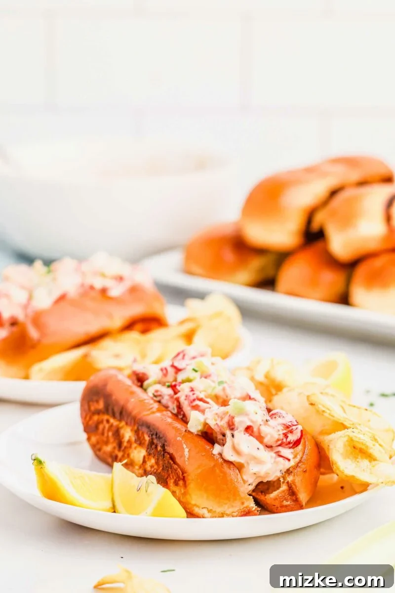 Heavenly Lobster Rolls 4 A beautifully presented lobster roll with lemon wedges and a side of potato chips on a white plate, ready to be served.
