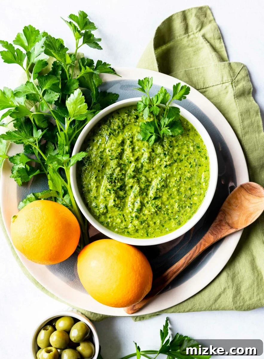 Vibrant Meyer Lemon Green Olive Gremolata 3 Herbs and lemons are placed next to a white bowl filled with gremolata.
