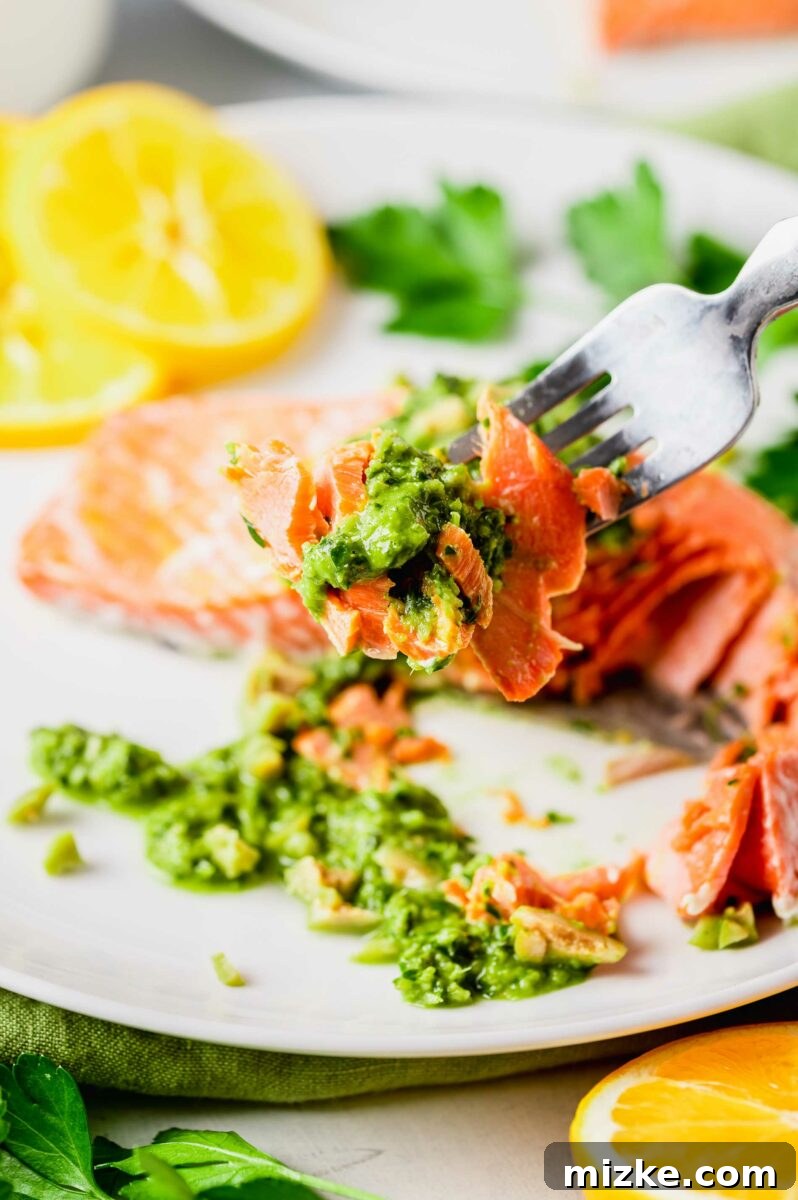 Zesty Green Olive Gremolata Roasted Salmon 5 A fork is lifting a bite of salmon and garnish from the plate.