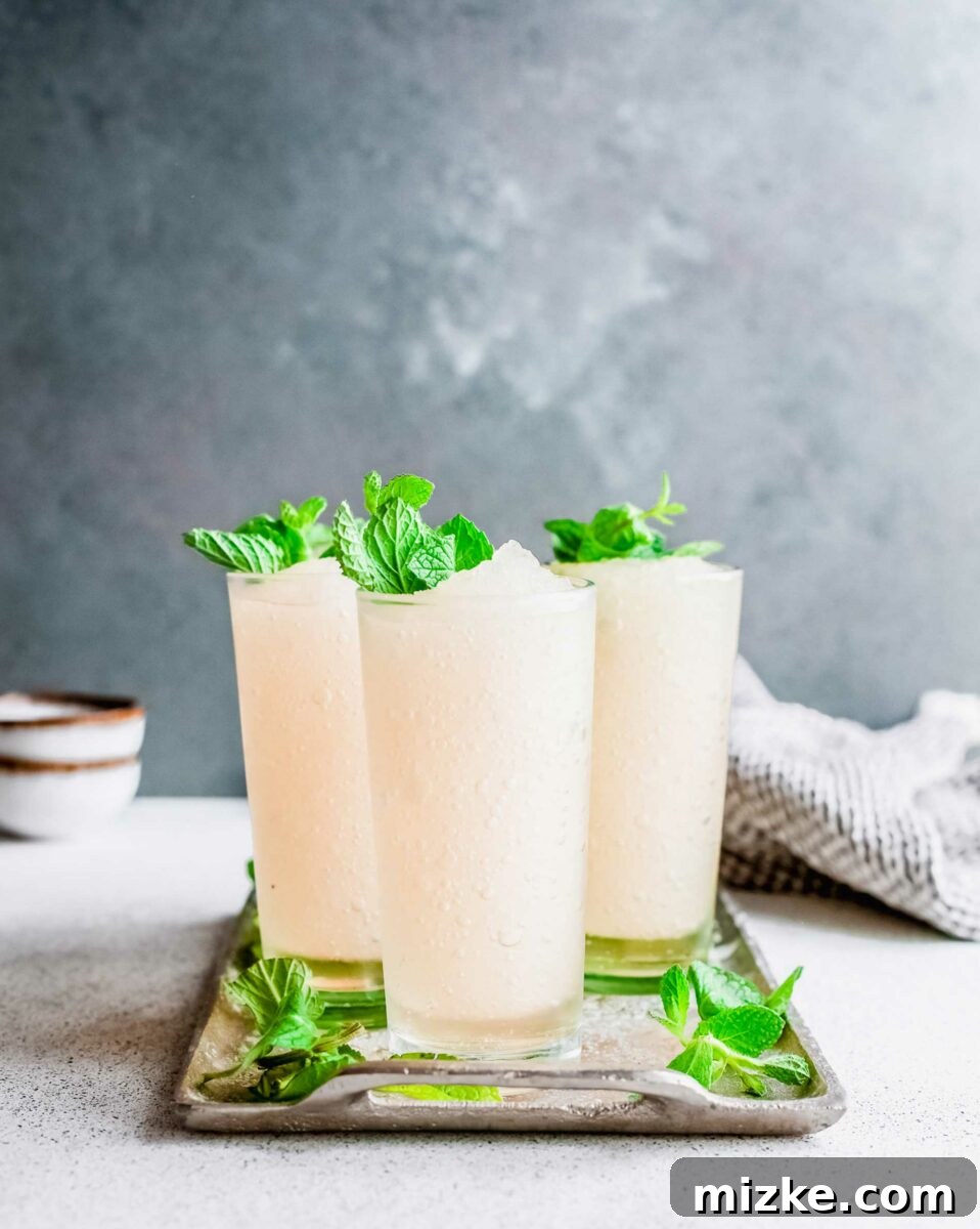 Minted Bourbon Frost 4 An elegant metal tray holds several cups filled with perfectly blended frozen mint julep, their frosty surfaces invitingly promising cool relief.