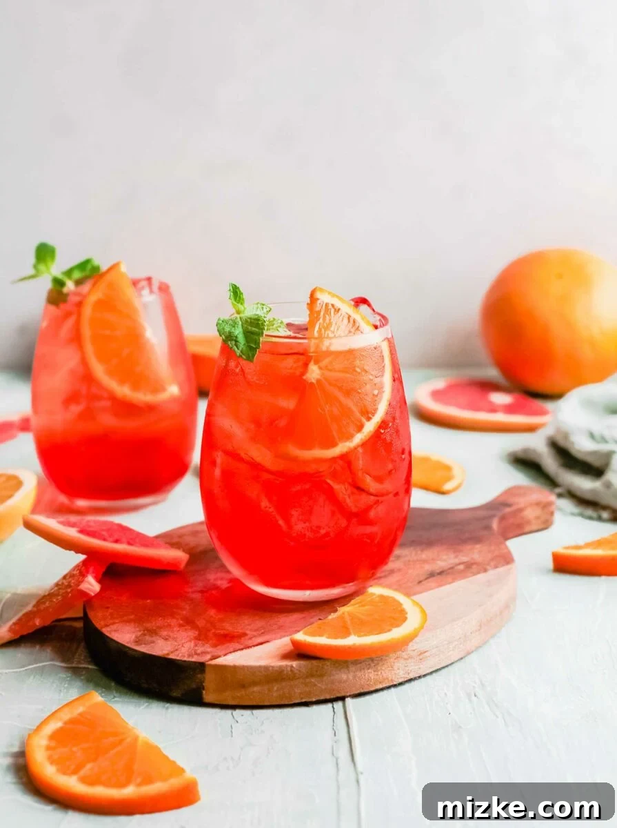 Sunkissed Citrus Sparkler 2 Two Aperol Spritzes are placed next to several orange slices, sparkling invitingly in golden light.