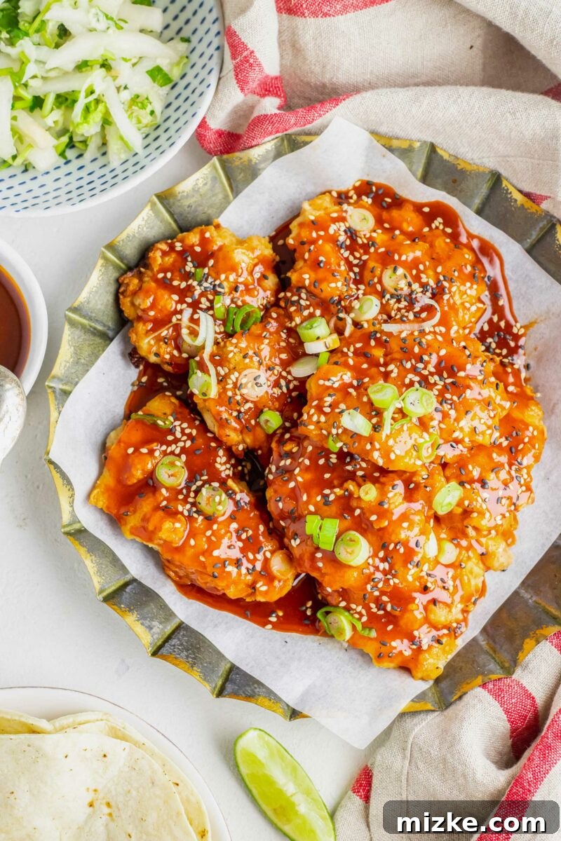 Chicken thighs are tossed in sauce and topped with scallions and sesame seeds. 