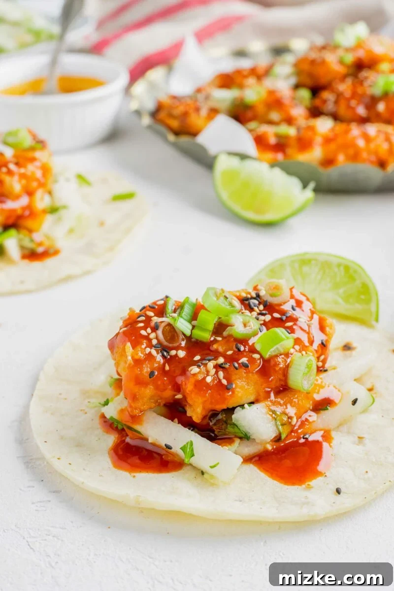 A piece of chicken is placed on top of pear slaw and a tortilla