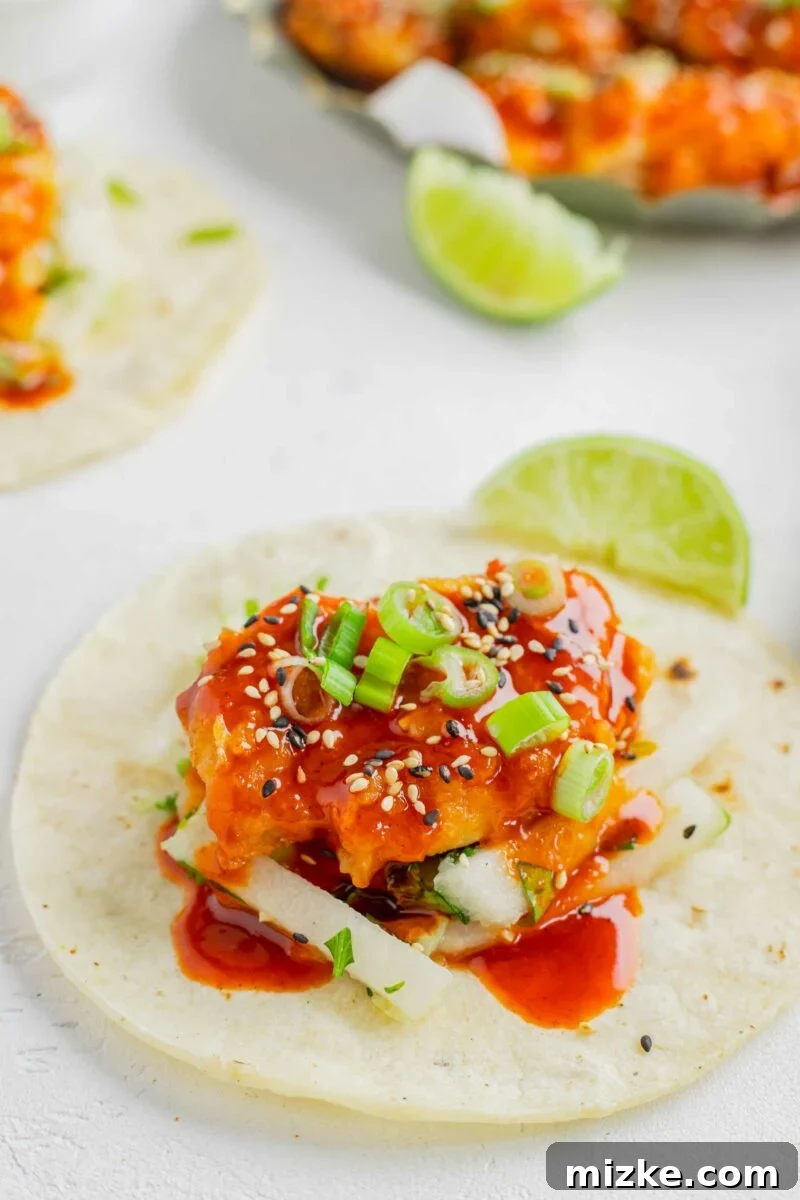 A corn tortilla is topped with slaw, chicken, and extra sauce. 