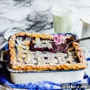 A close-up of a spatula lifting a piece of deep dish wild blueberry pie, showcasing the luscious, juicy filling and golden-brown, flaky crust.