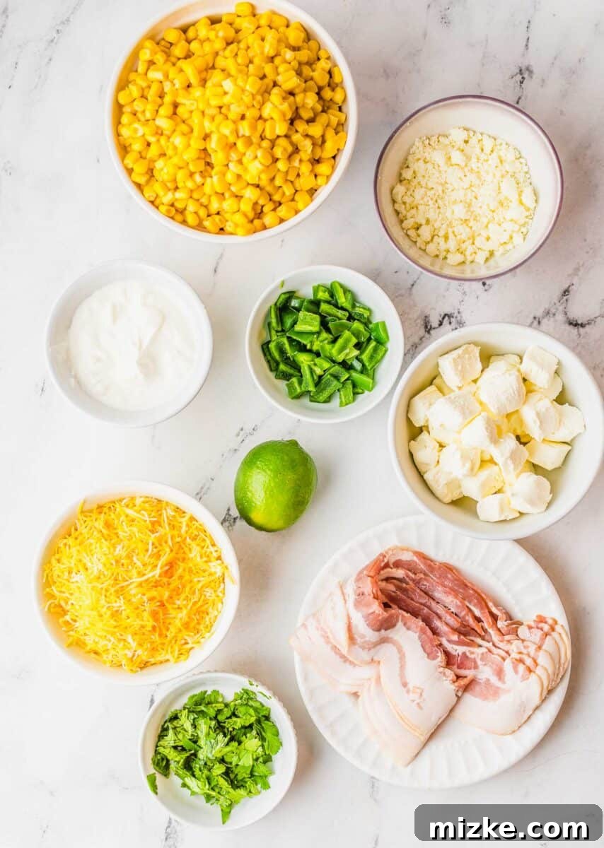 A collection of fresh ingredients for jalapeno corn dip, including corn, jalapeños, cheeses, sour cream, and cilantro, laid out on a wooden surface.