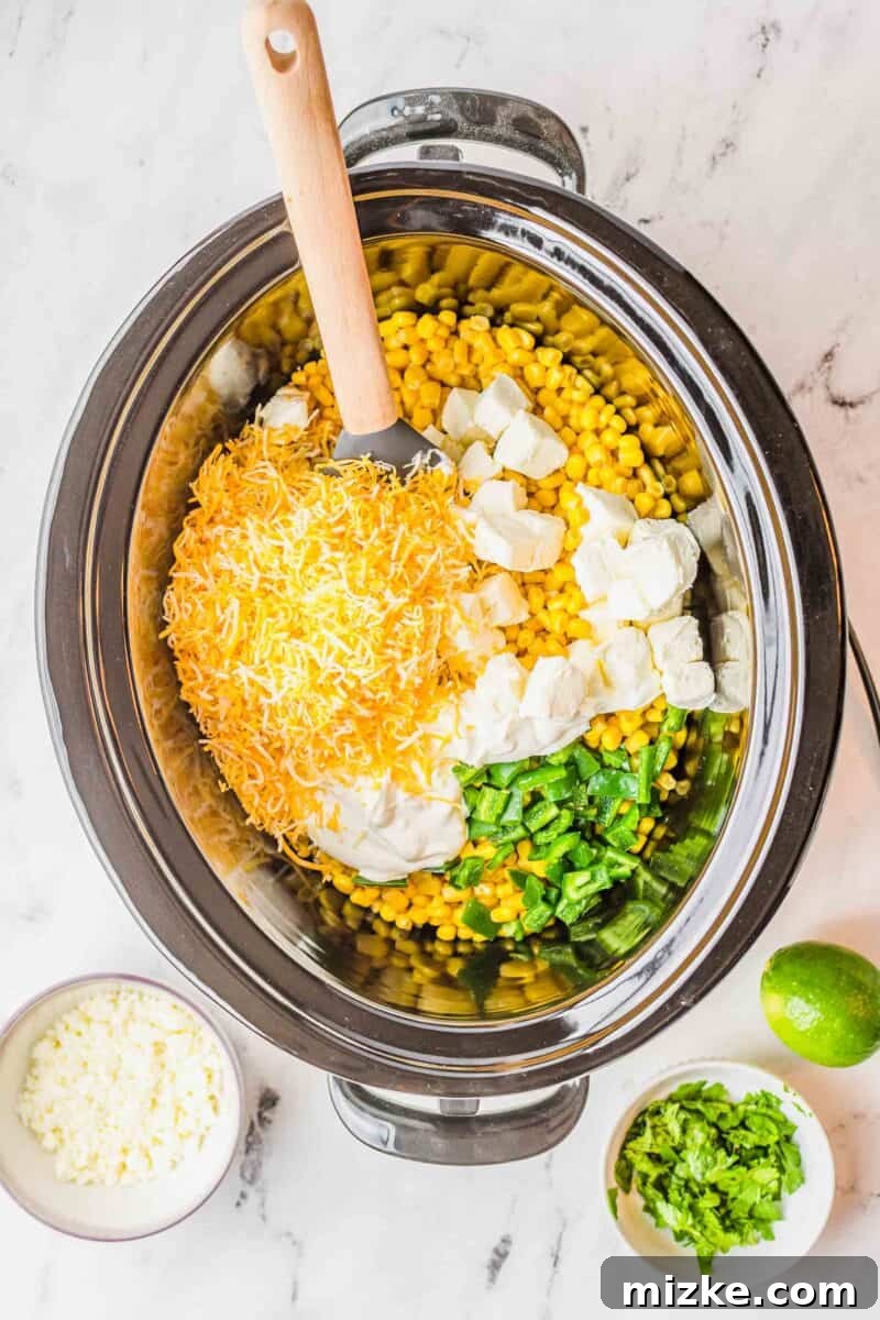 Uncooked ingredients for jalapeno corn dip, including corn, jalapeños, and cheeses, are added to the insert of a slow cooker before mixing.